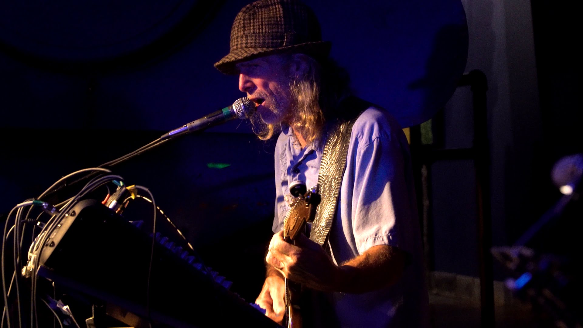 Jim at the mic, blue-lit stage